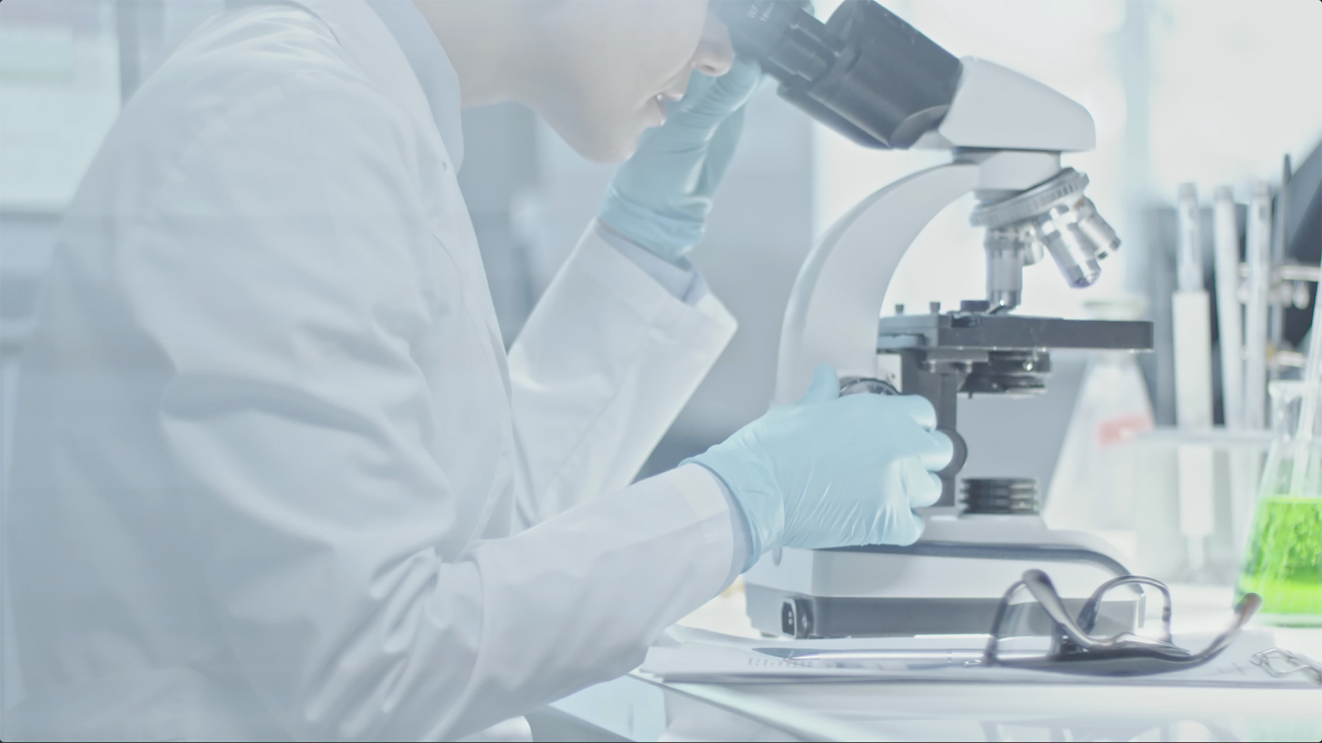 scientist looking through microscope in lab