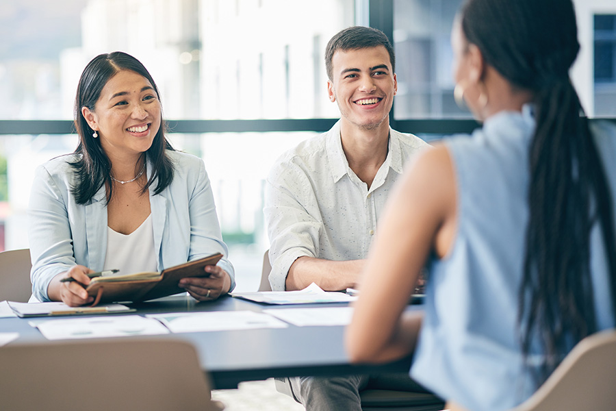3 people smiling at a desk